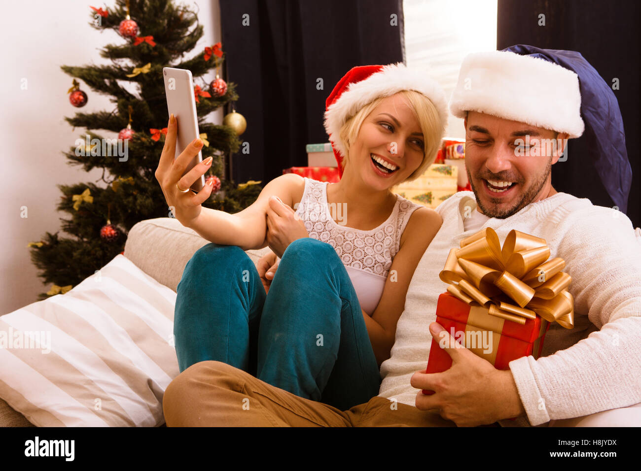 Happy Christmas couple faisant l'auto des photos à la maison Banque D'Images