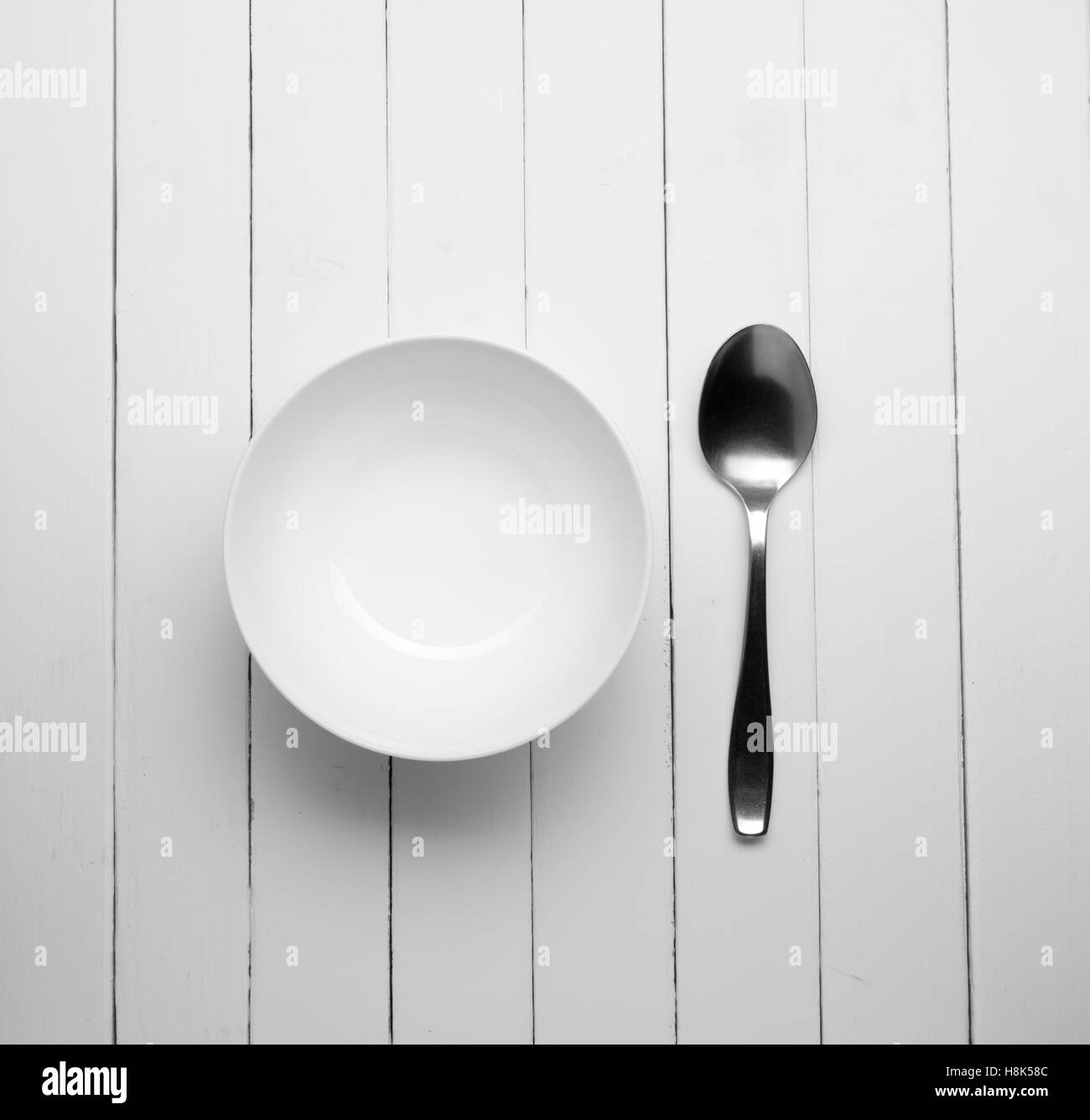 Plat blanc sur une table en bois avec une vieille cuillère, espace libre pour le texte. La photographie noir et blanc Banque D'Images Plat blanc sur une table en bois avec une vieille cuillère, espace libre pour le texte. La photographie noir et blanc Banque D'Images