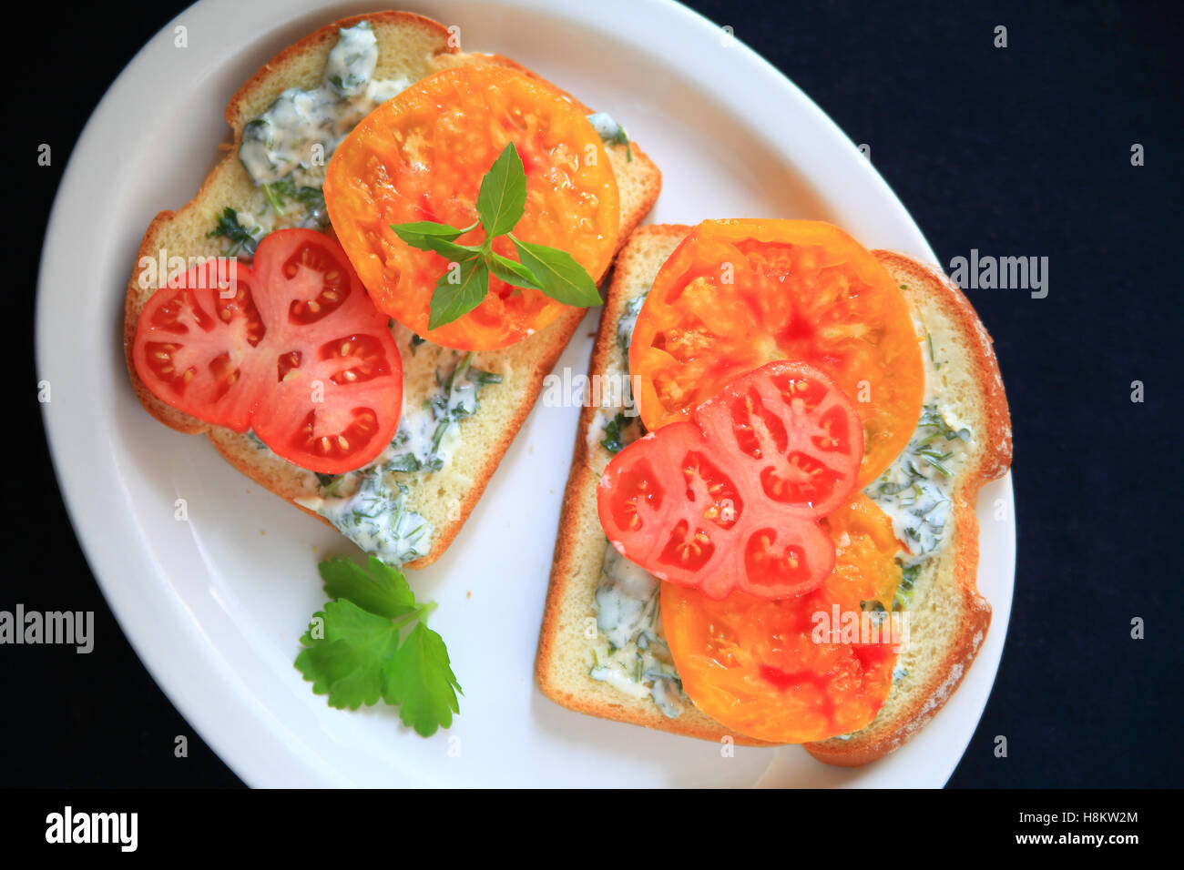 Sandwich tomate tomates heirloom avec avec la coriandre mayonnaise sur un plateau blanc Banque D'Images