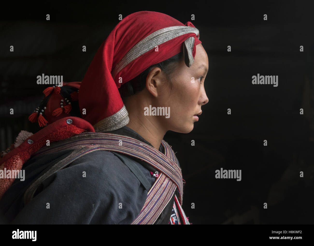 Jeune femme Dao Rouge avec bébé au dos éclairée par une porte, Sa Pa, Vietnam du Nord Banque D'Images