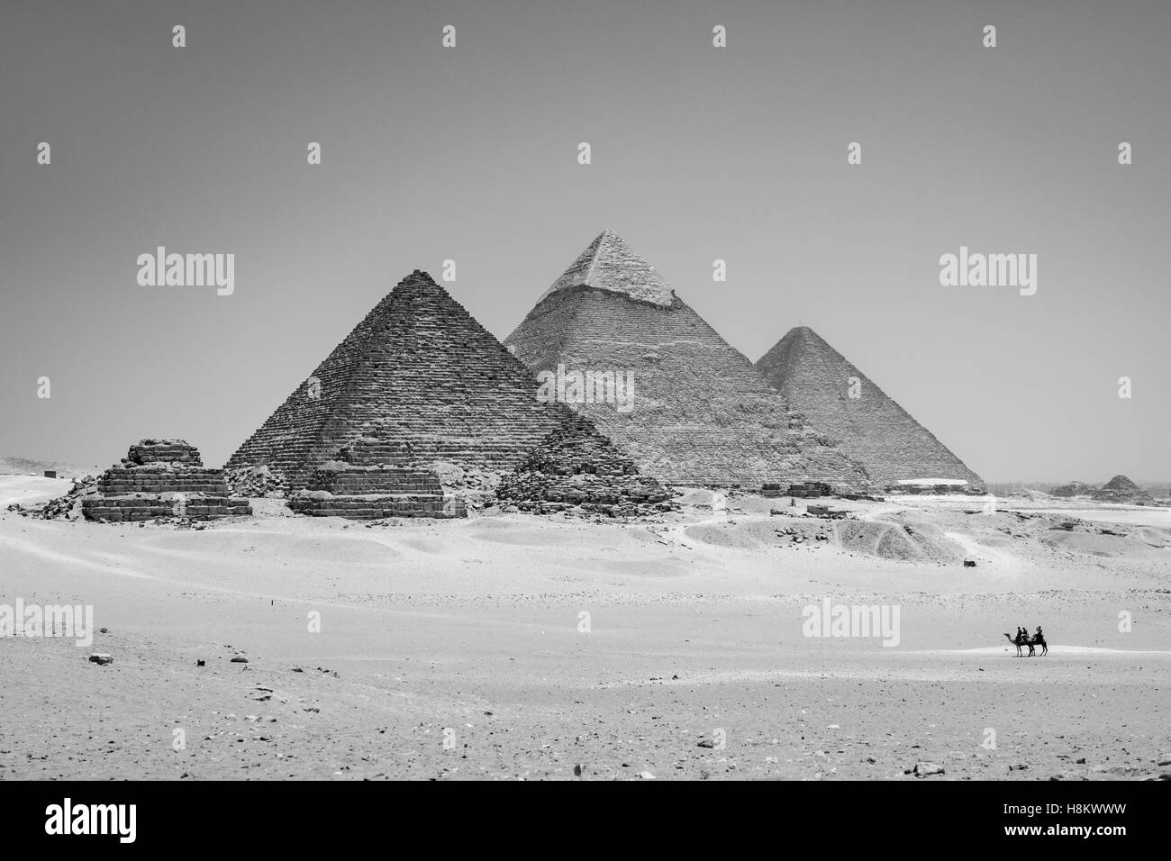 Le Caire, Egypte vaste désert du Sahara avec deux chameliers avec les trois grandes pyramides de Gizeh à l'arrière-plan. De gauche à rig Banque D'Images