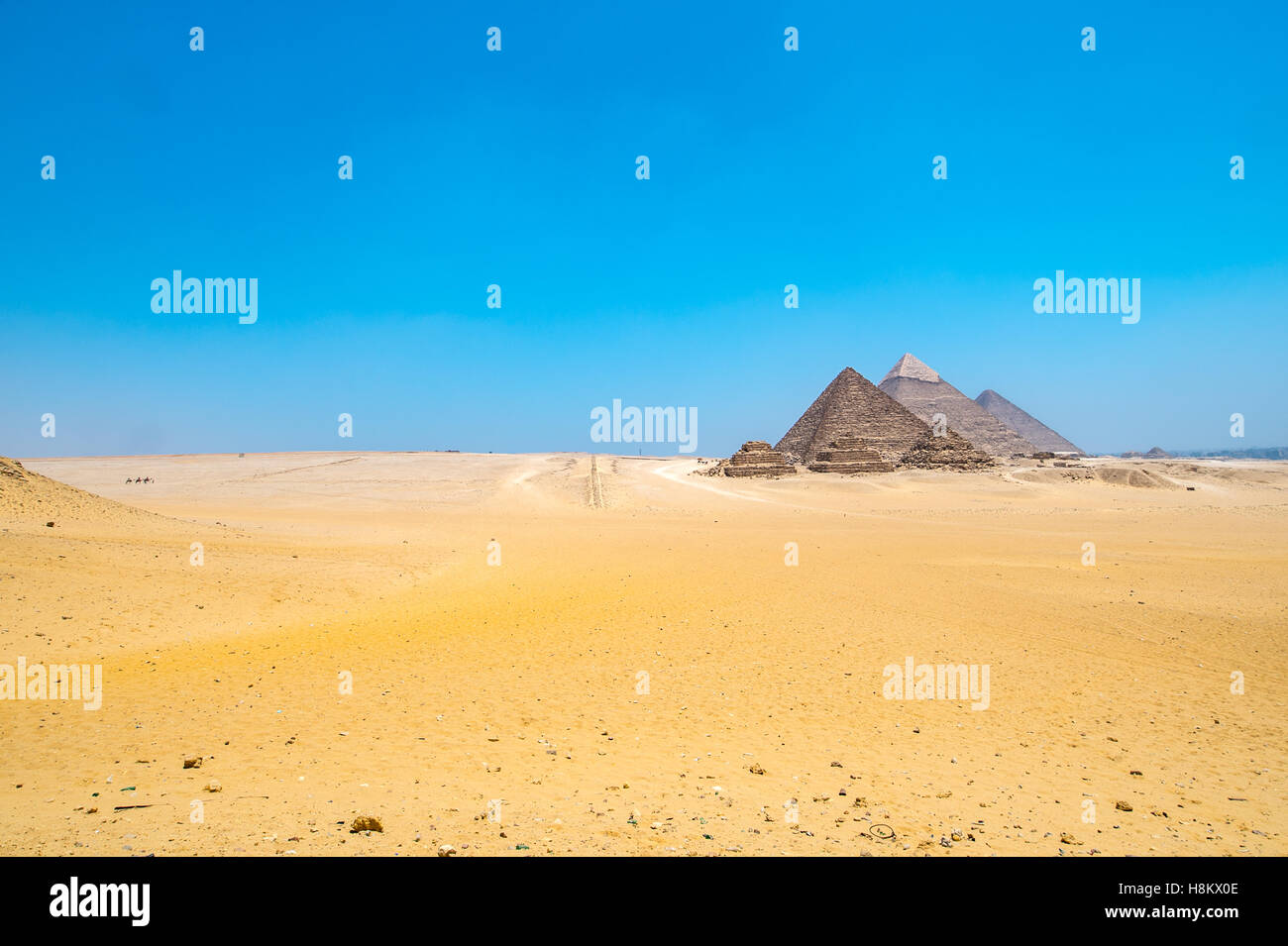 Le Caire, Egypte vaste désert du Sahara avec les trois grandes pyramides de Gizeh à l'arrière-plan contre un ciel bleu clair. De gauche à r Banque D'Images