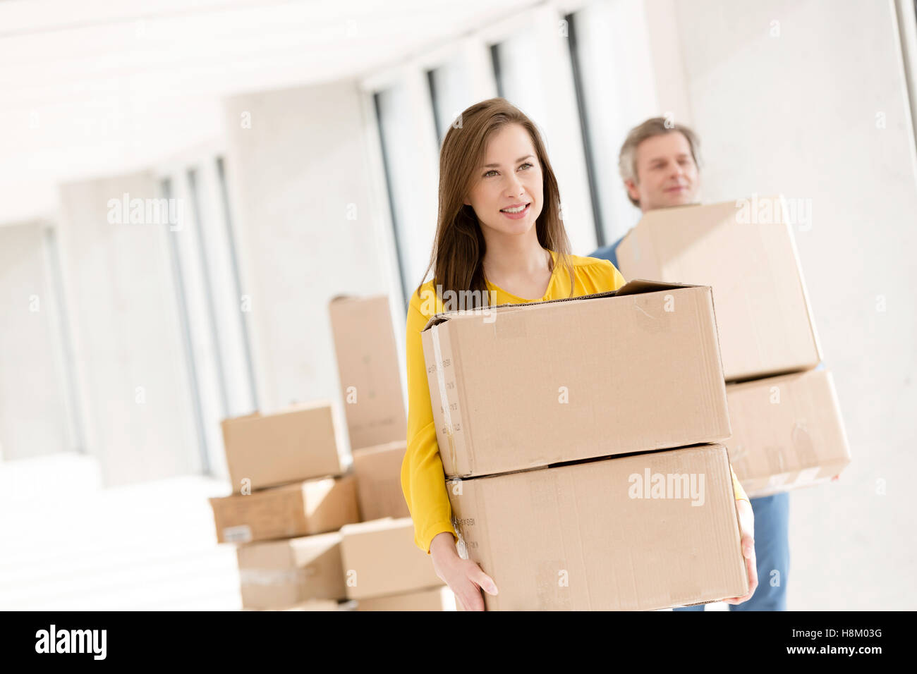 Young businesswoman with collègue masculin carrying cardboard boxes in new office Banque D'Images