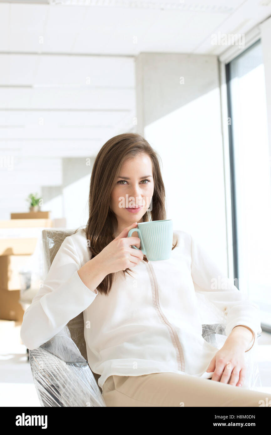 Portrait de belle jeune businesswoman drinking coffee in nouveau bureau Banque D'Images Portrait de belle jeune businesswoman drinking coffee in nouveau bureau Banque D'Images