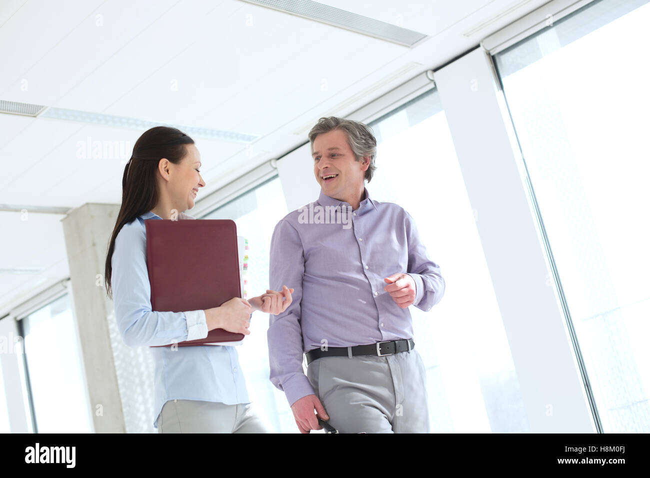 Smiling businessman talking with female colleague in office Banque D'Images