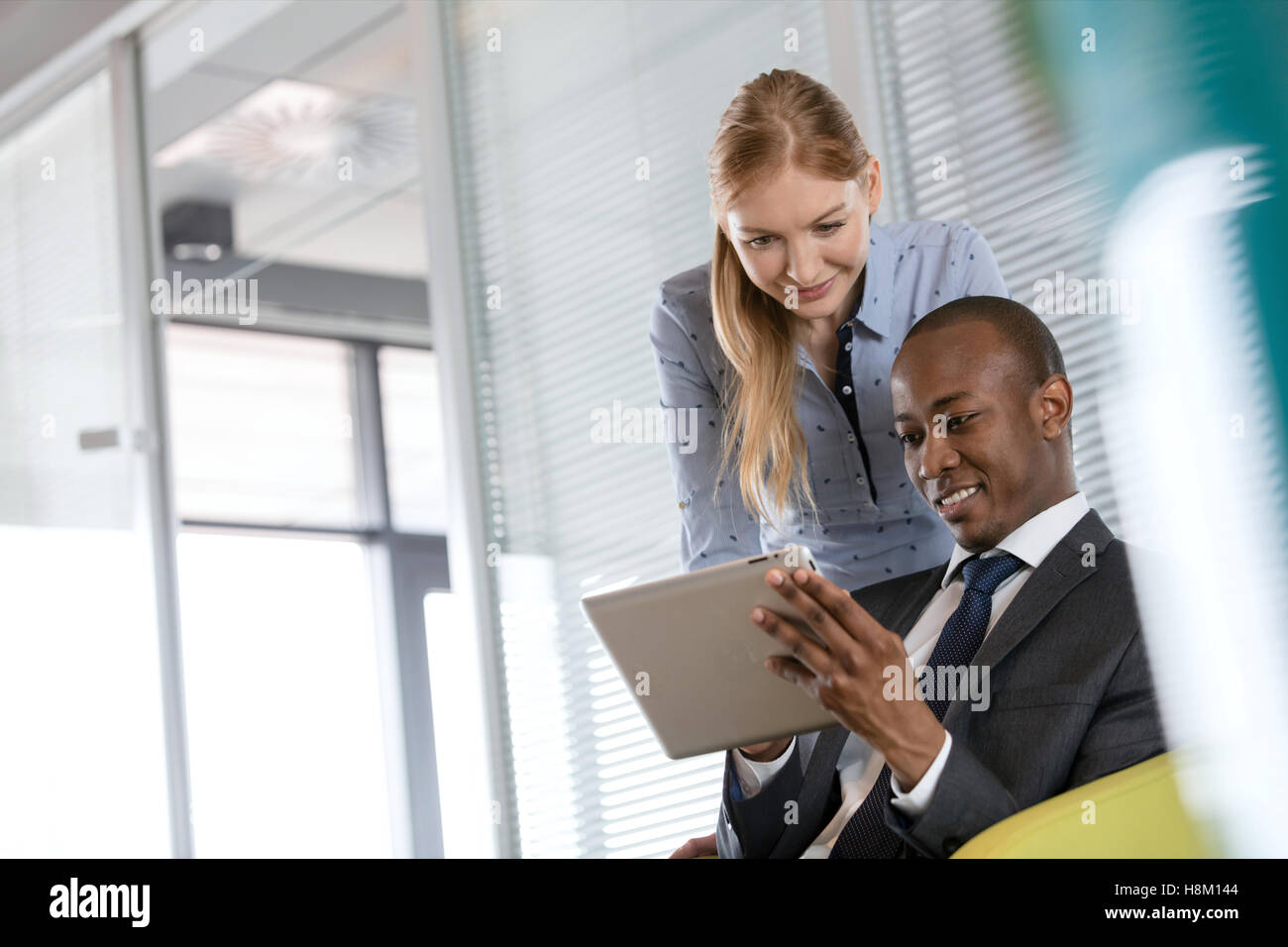 Smiling young businesswoman with male colleague using digital tablet in office Banque D'Images