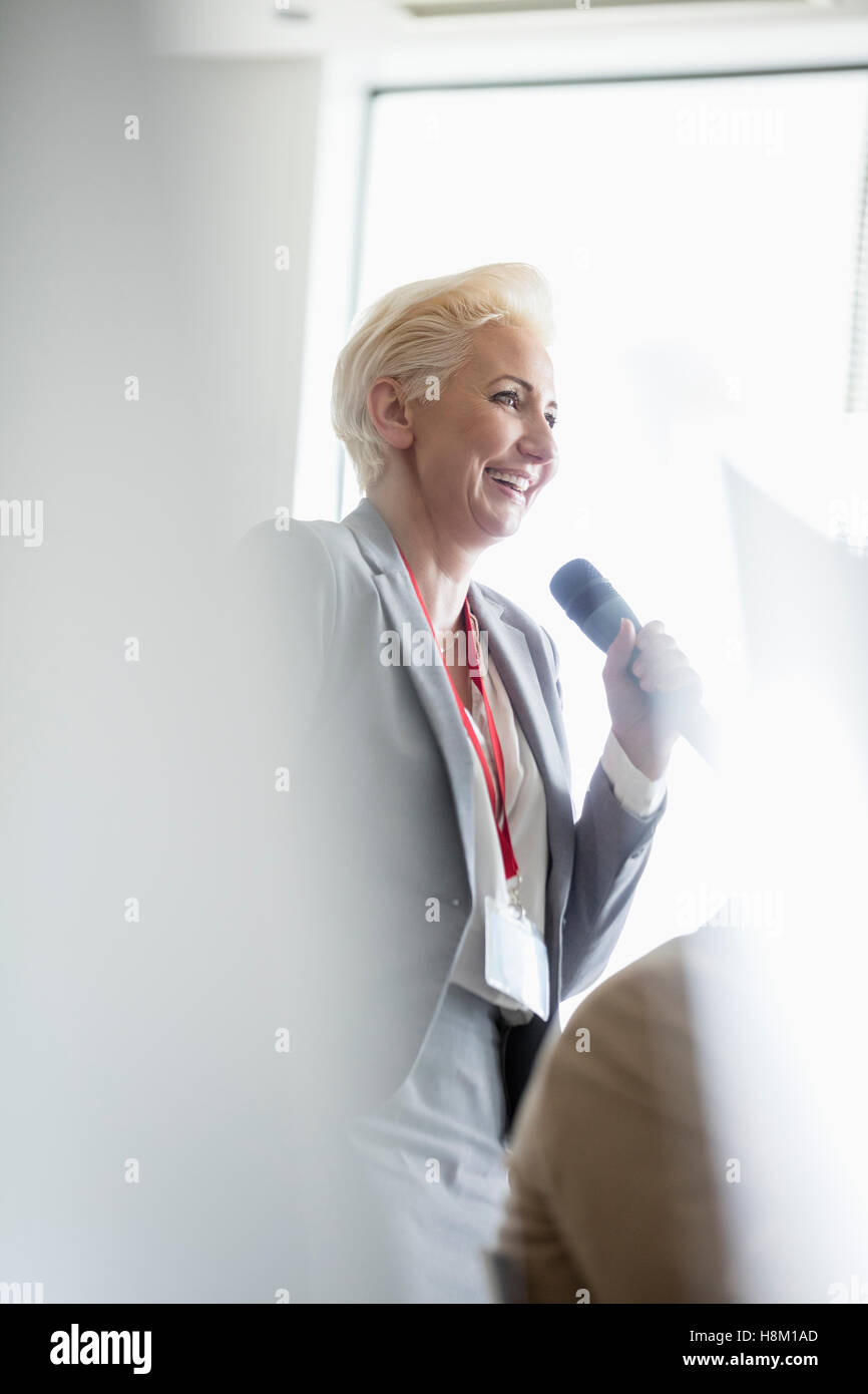 Happy businesswoman parlant à travers le microphone pendant séminaire Banque D'Images