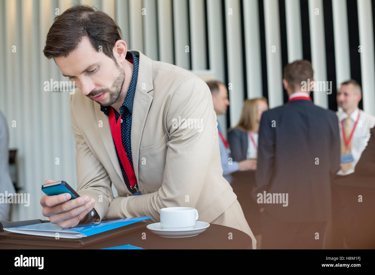 Businessman using smart phone tout en pause café au Convention Center Banque D'Images Businessman using smart phone tout en pause café au Convention Center Banque D'Images
