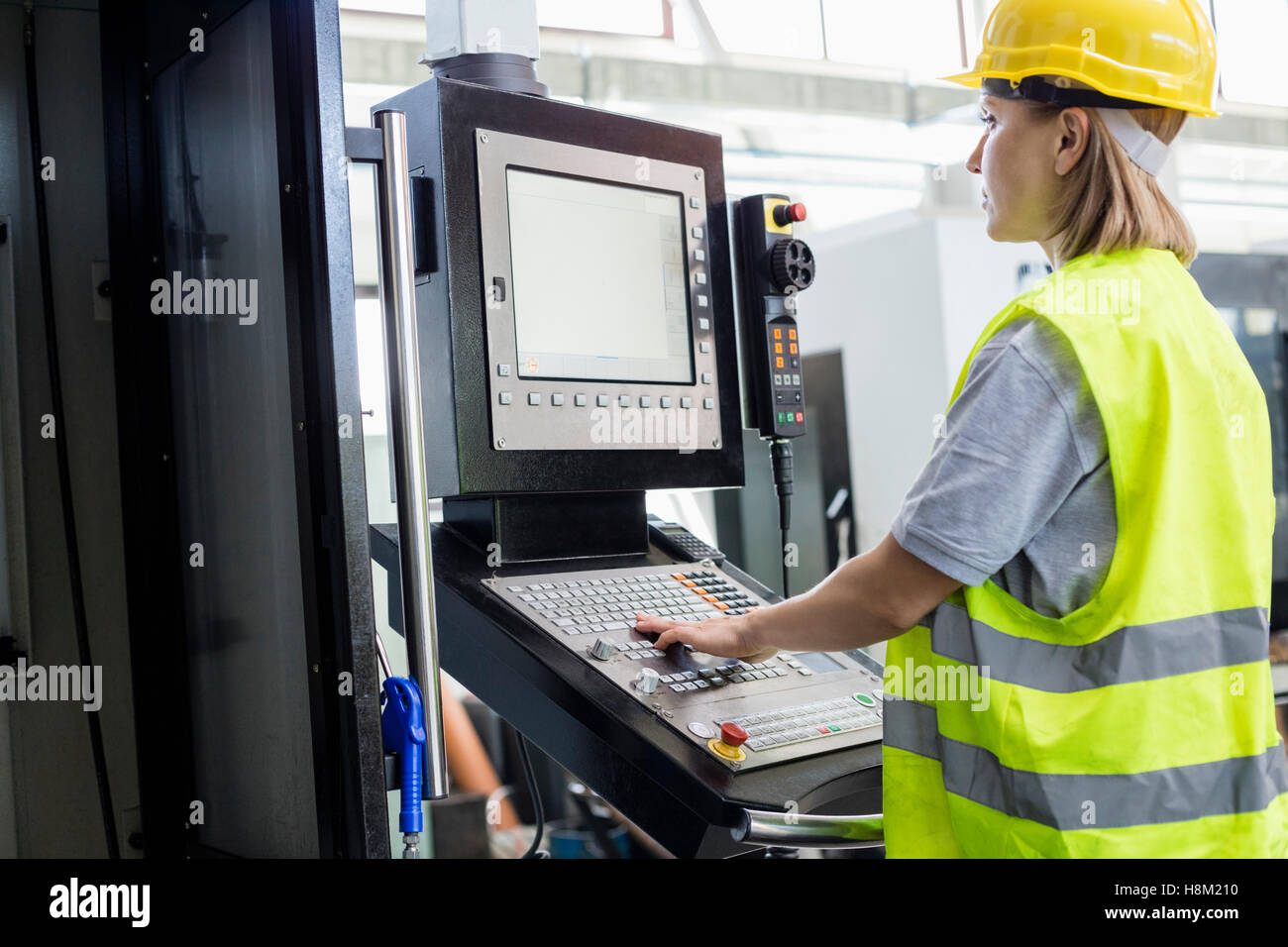 Vue latérale du travailleur féminin l'utilisation de machines sur le panneau en usine Banque D'Images