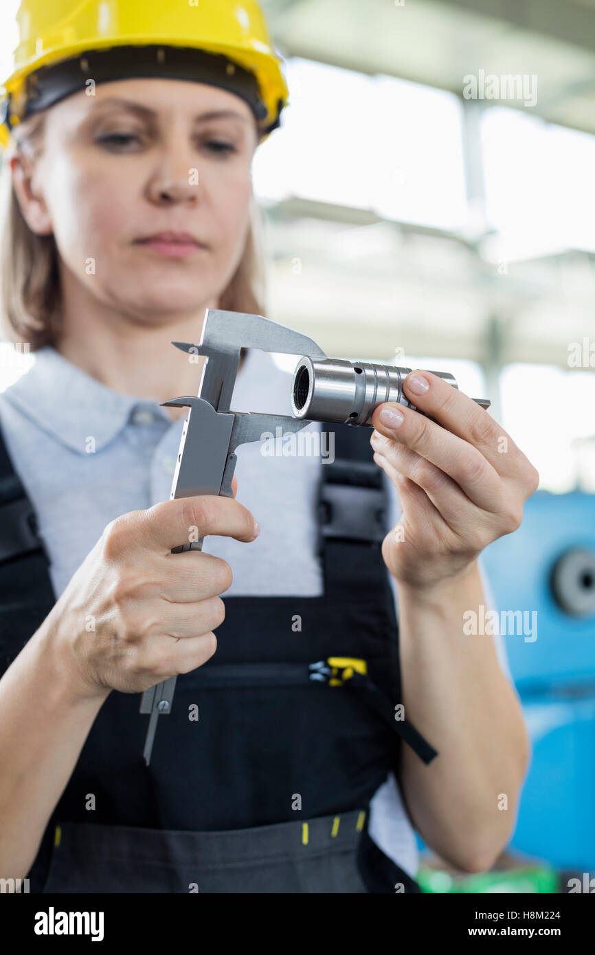 Femelle adulte mesure de travailleurs en usine d'étrier avec métal Banque D'Images