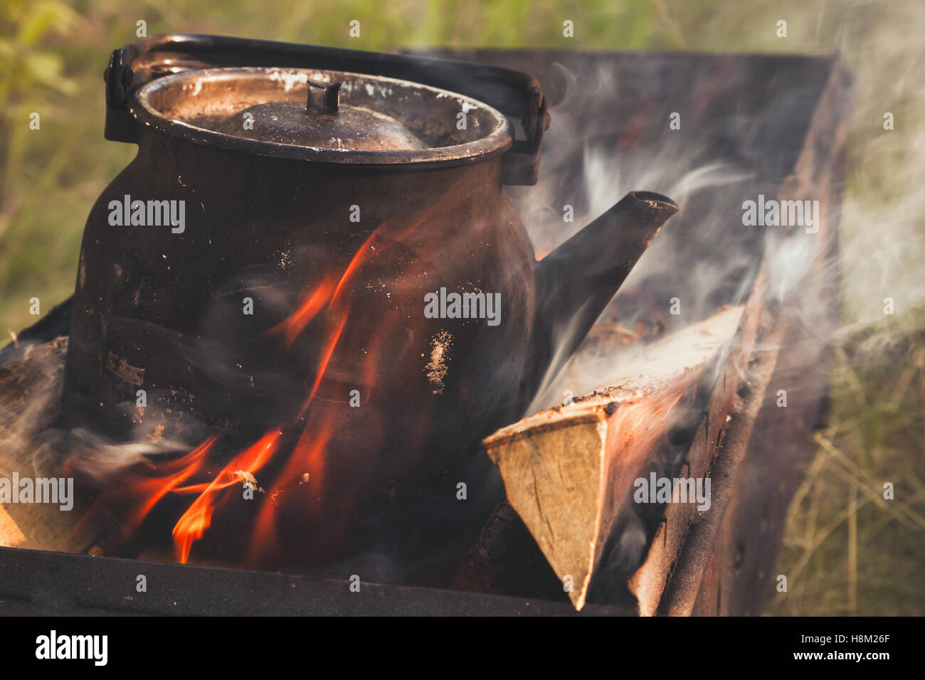 Vieille théière bouillante noir se dresse sur Bonfire, retro photo stylisée avec effet de filtre de correction tonale, old style Banque D'Images