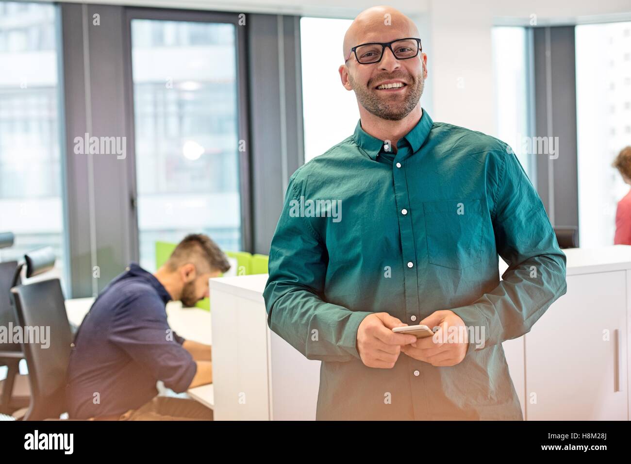 Portrait of Mid adult businessman smiling with colleague in office Banque D'Images