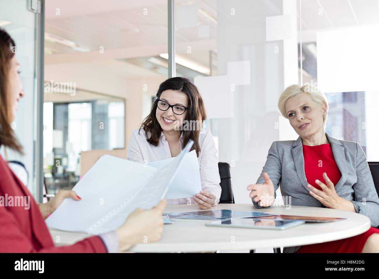 Femme mature en train de discuter avec des collègues de sexe féminin à table in office Banque D'Images