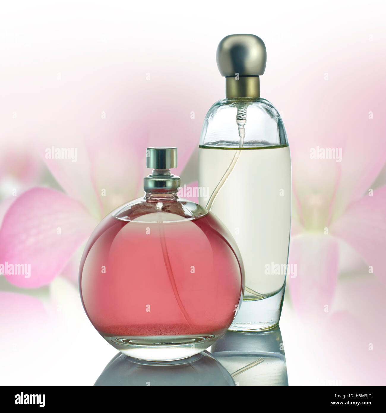 Flacons de parfum avec des fleurs roses sur fond blanc Banque D'Images
