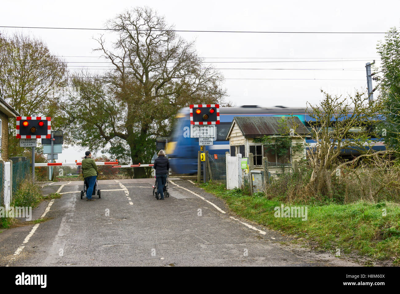 Deux femmes avec des poussettes d'enfants en attente de traverser la ligne de chemin de fer Milton Cambridge Cambridgeshire England UK 2016 Banque D'Images