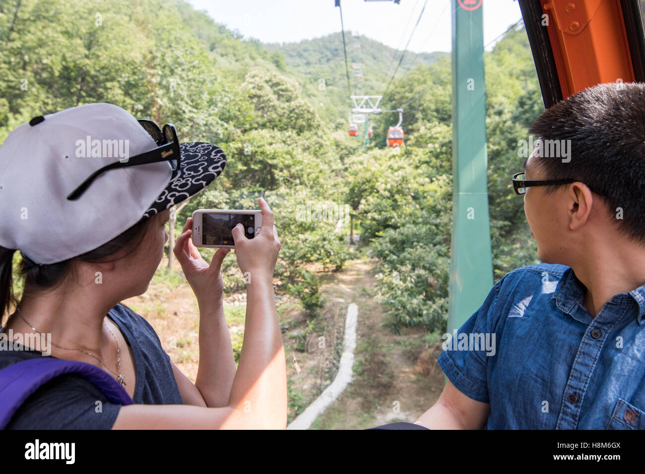 Mutianyu, Chine - touristes prenant des photos sur leur téléphone cellulaire pendant la conduite le télésiège jusqu'à la Grande Muraille de Chine. La wal Banque D'Images