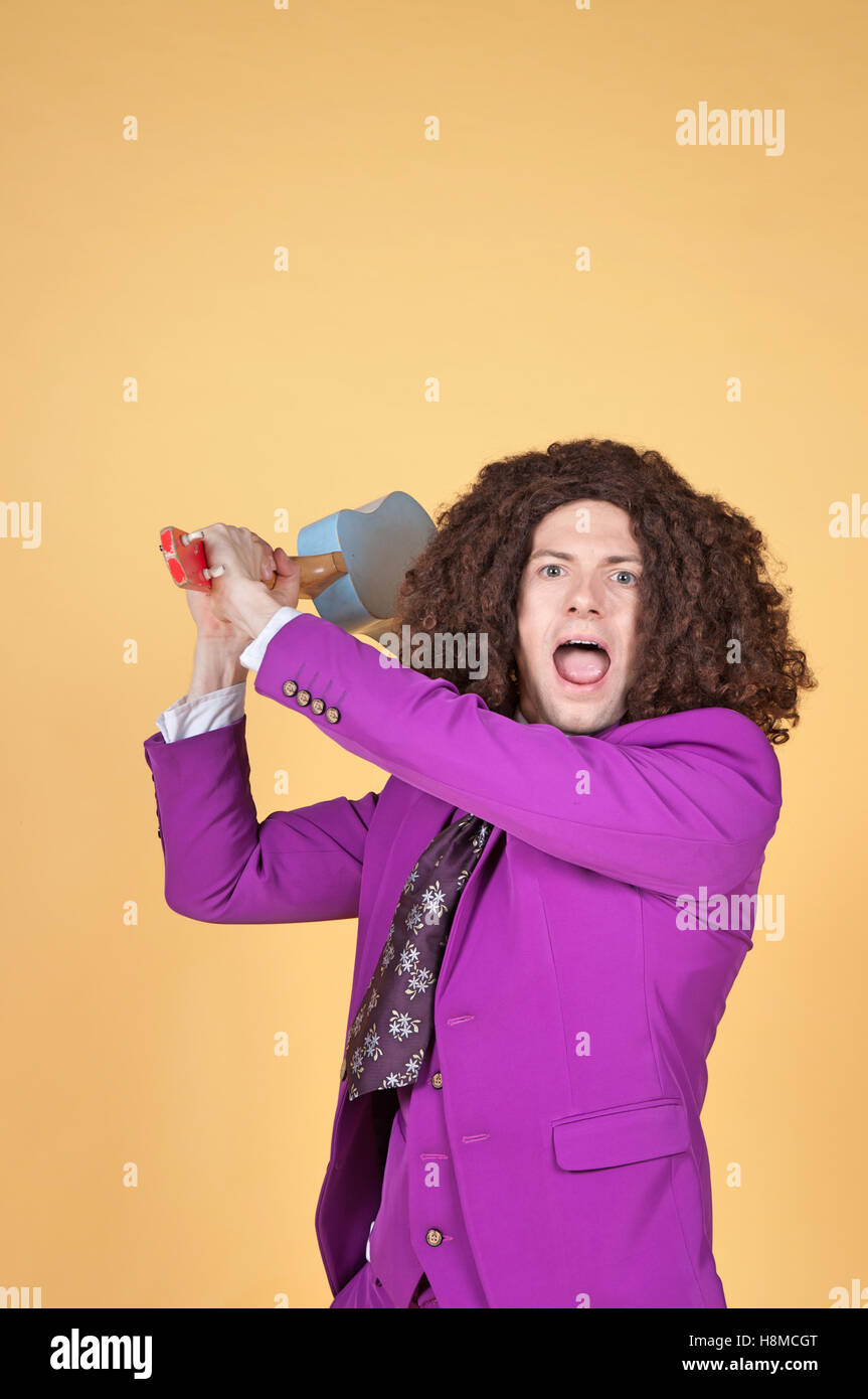 Caucasian man with afro portant costume violet avec la guitare derrière sa tête Banque D'Images