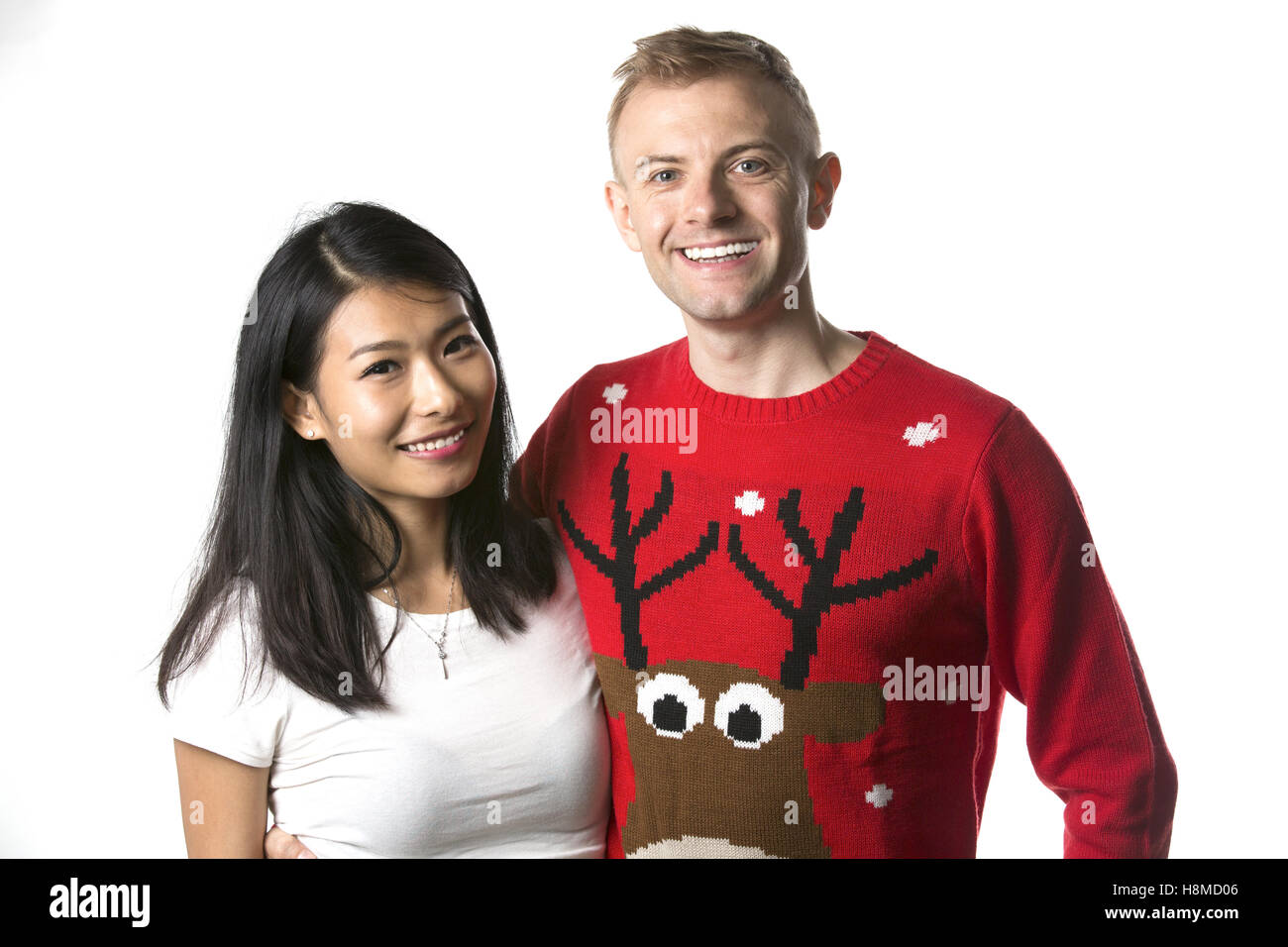 Portrait of happy multi ethnic couple wearing christmas jumpers en studio Banque D'Images
