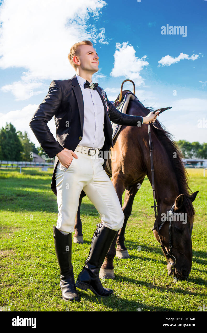Longueur totale du bien-habillé homme debout à cheval sur terrain Banque D'Images