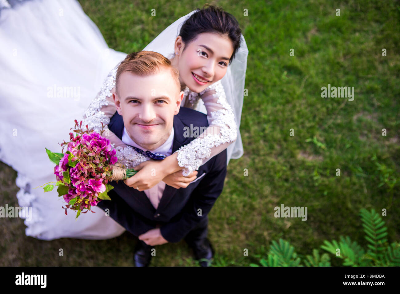 High angle portrait of happy wedding couple standing on grassy field Banque D'Images