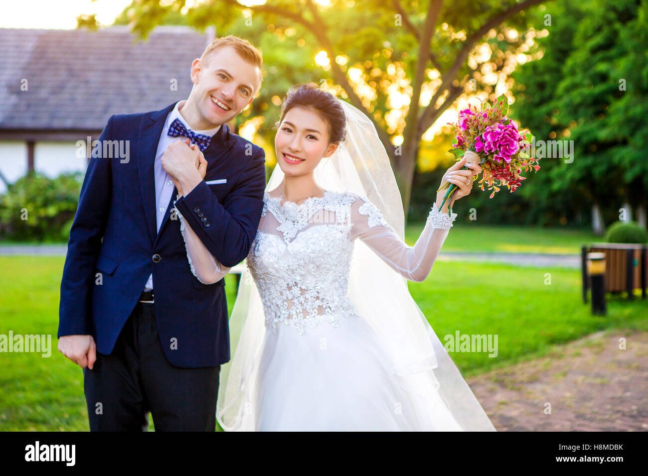 Portrait of happy wedding couple holding hands while standing à lawn Banque D'Images
