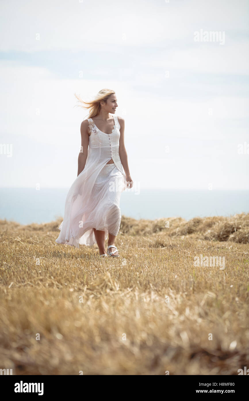 Blonde woman walking in field près d'une rivière Banque D'Images