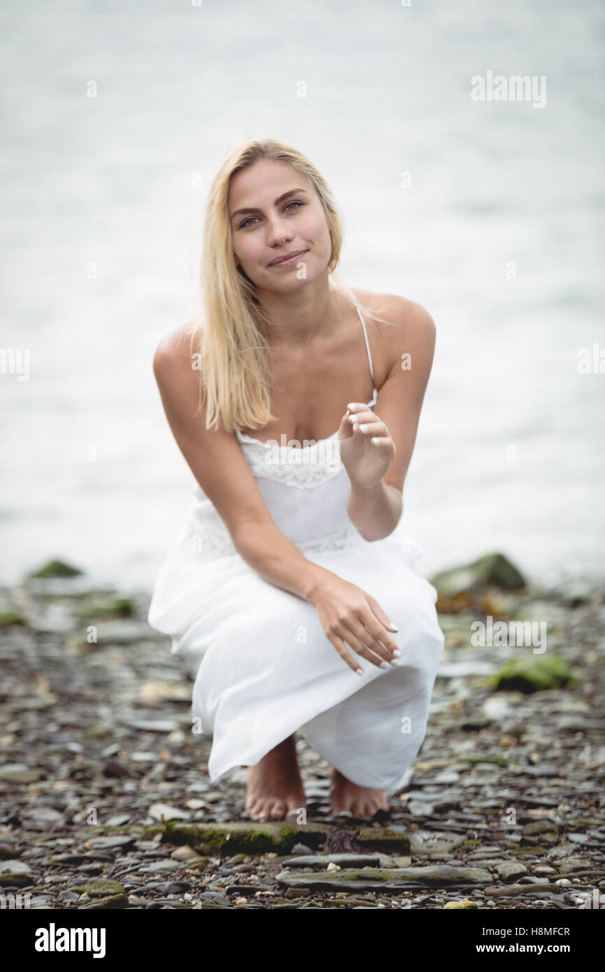 Carefree woman crouching près d'une rivière Banque D'Images