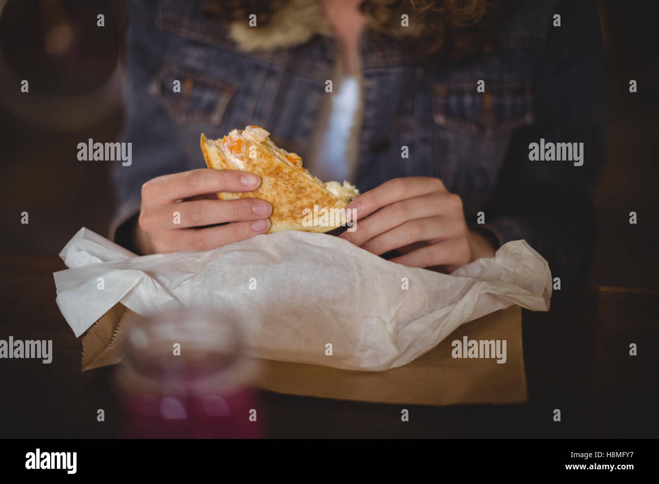 Femme assise à table et de manger un sandwich au magasin de vélos Banque D'Images