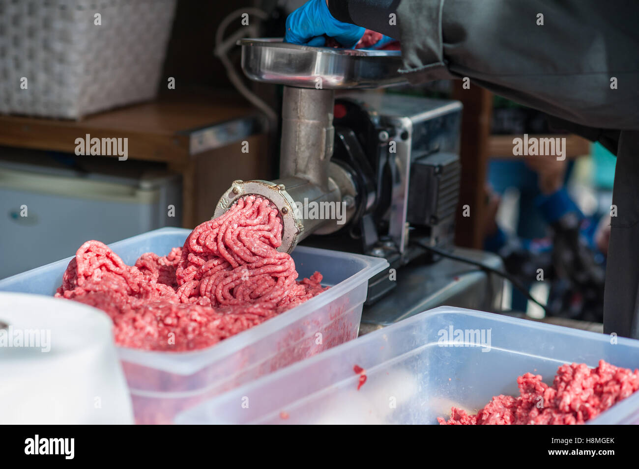 Plateau de viande hachée fraîche. Butcher hachoir à viande à la main et à la machine qui met la viande dans la machine. Banque D'Images