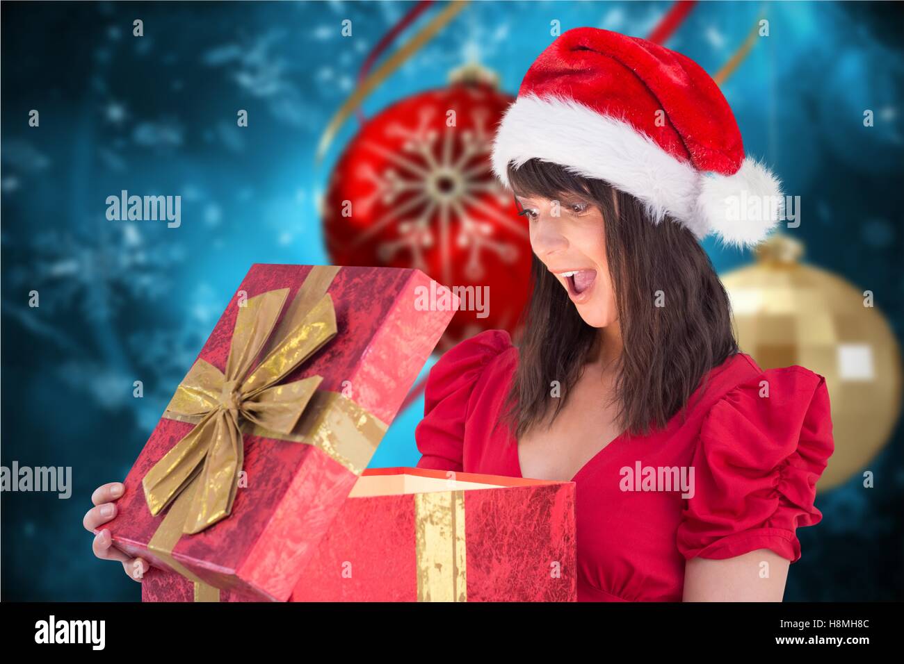 Surprised woman in santa hat looking at Christmas gifts Banque D'Images