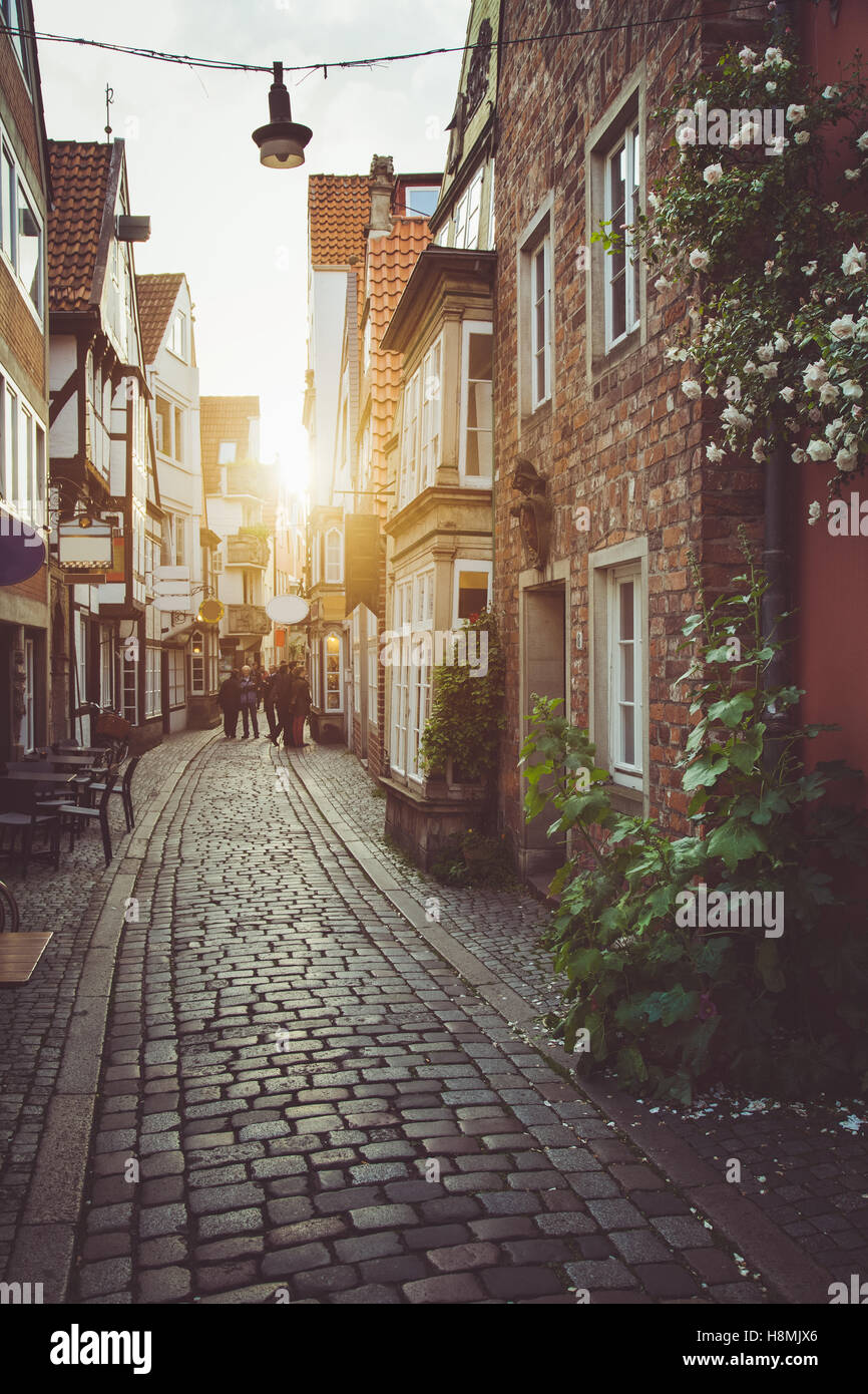 Scène de rue enchanteresse dans une ancienne ville d'Europe au coucher du soleil avec des tons pastel vintage rétro et lens flare filtre effet de soleil Banque D'Images