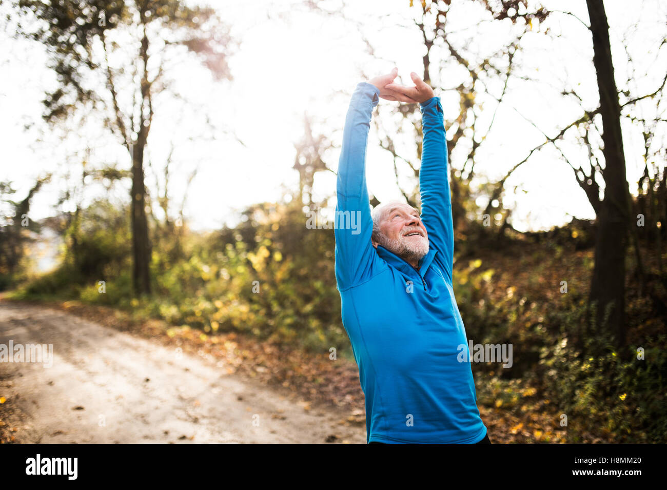 Hauts runner doing stretching dans la nature ensoleillée d'automne. Banque D'Images