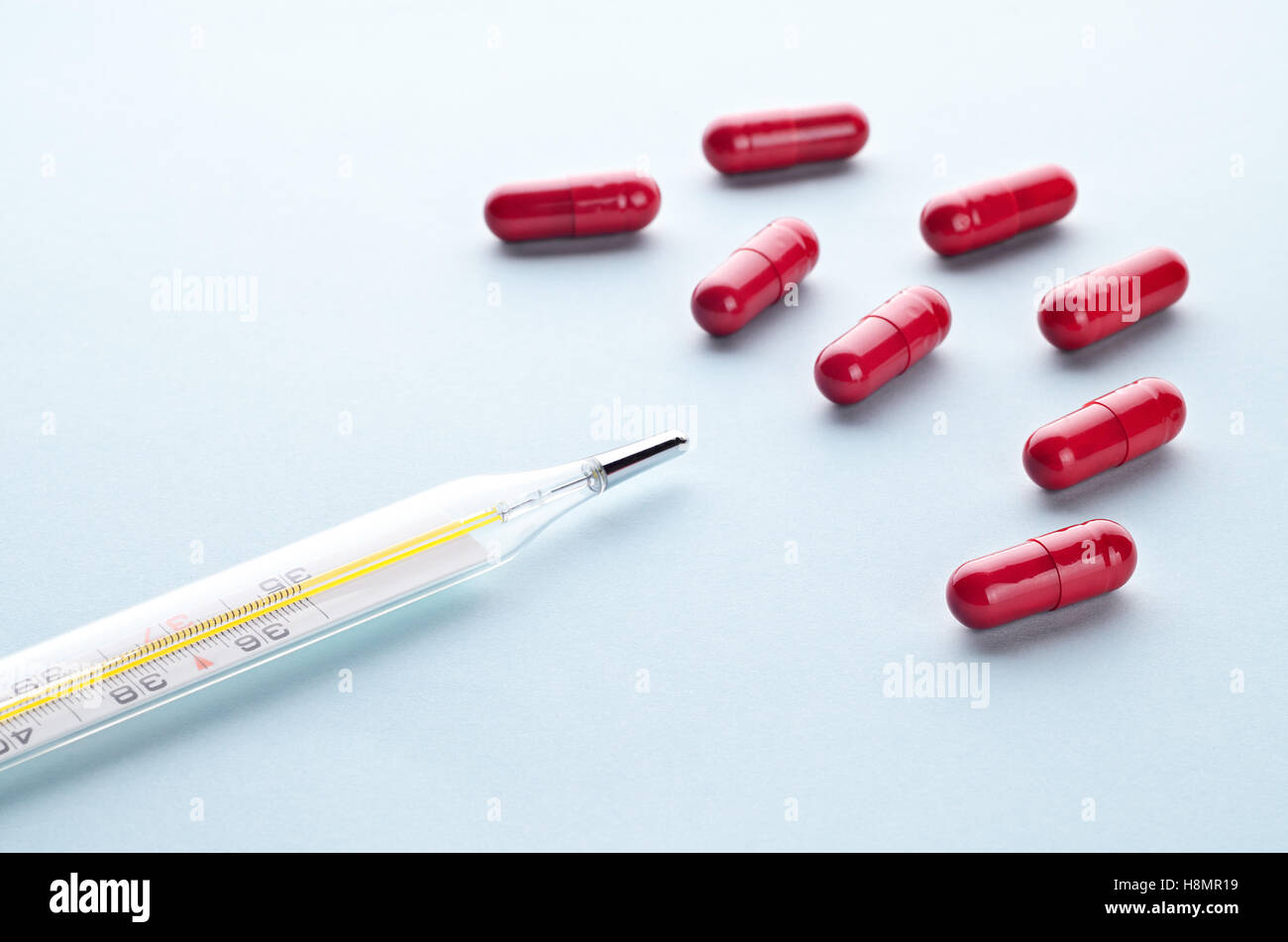 Colorés assortis des antipyrétiques comprimés, capsules et thermomètre sur un fond clair close up, horizontal, concept médical Banque D'Images