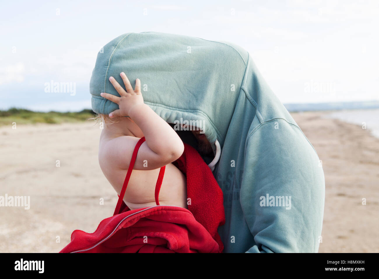 Girl (2-3) se cachant dans père hooded shirt Banque D'Images