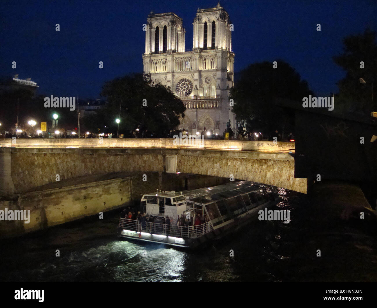 La cathédrale notre Dame s'illumine la nuit et un bateau à passagers le long de la Seine, Paris, France. Banque D'Images