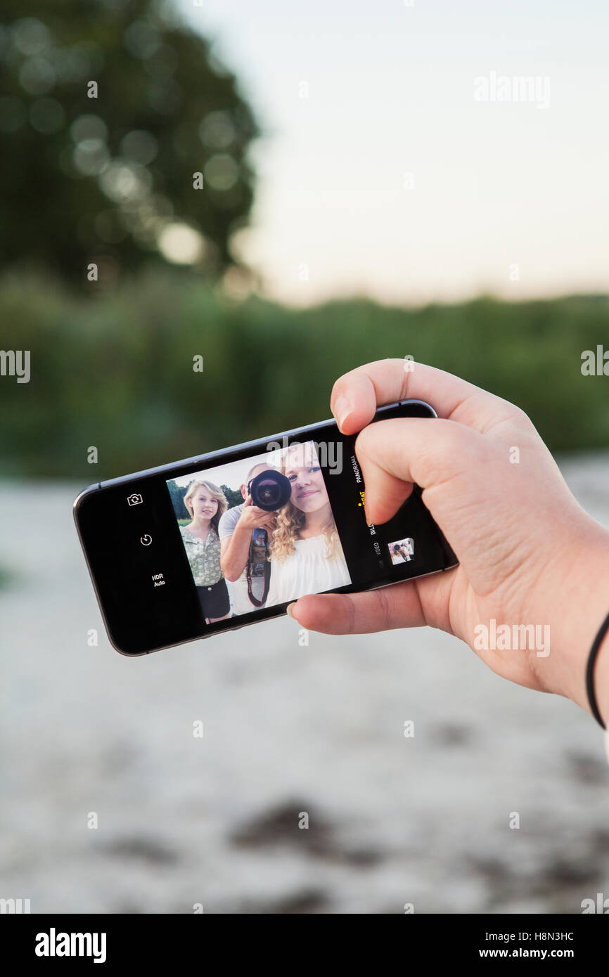 Hand holding mobile avec photo d'un homme avec deux filles (14-15, 16-17) Banque D'Images