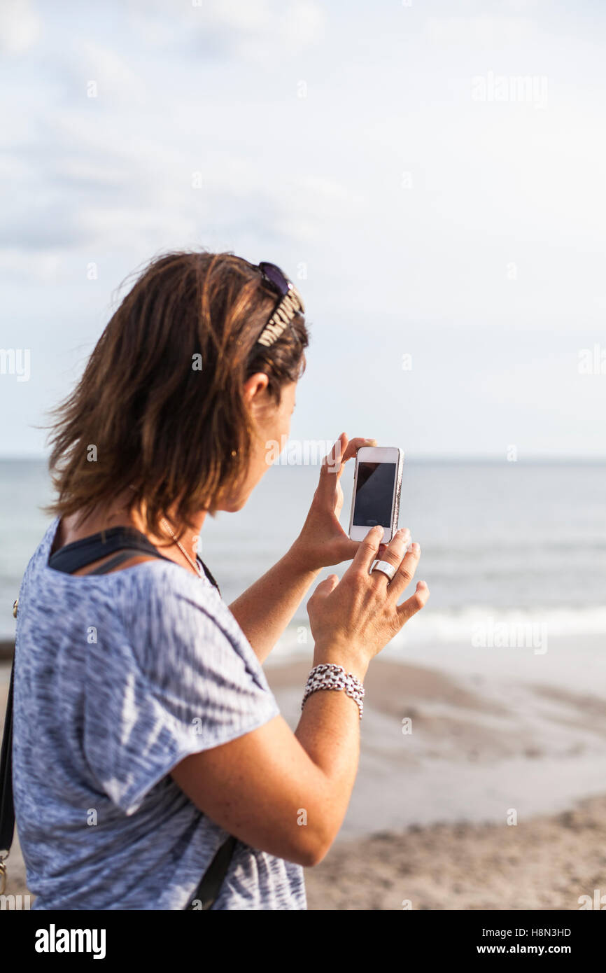 Woman taking photo de téléphone à l'aide de la mer Banque D'Images