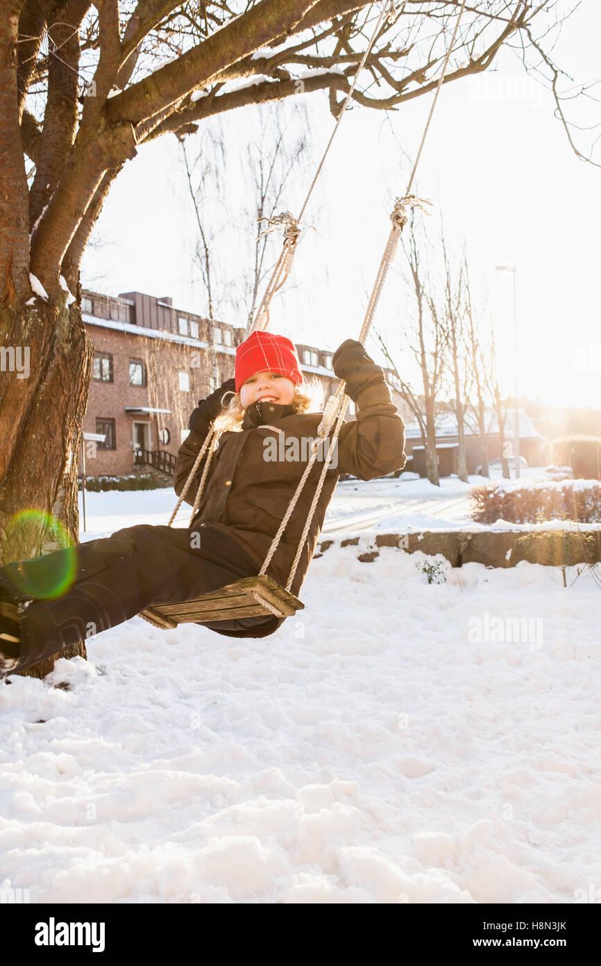 Girl (8-9) sitting on rope swing Banque D'Images