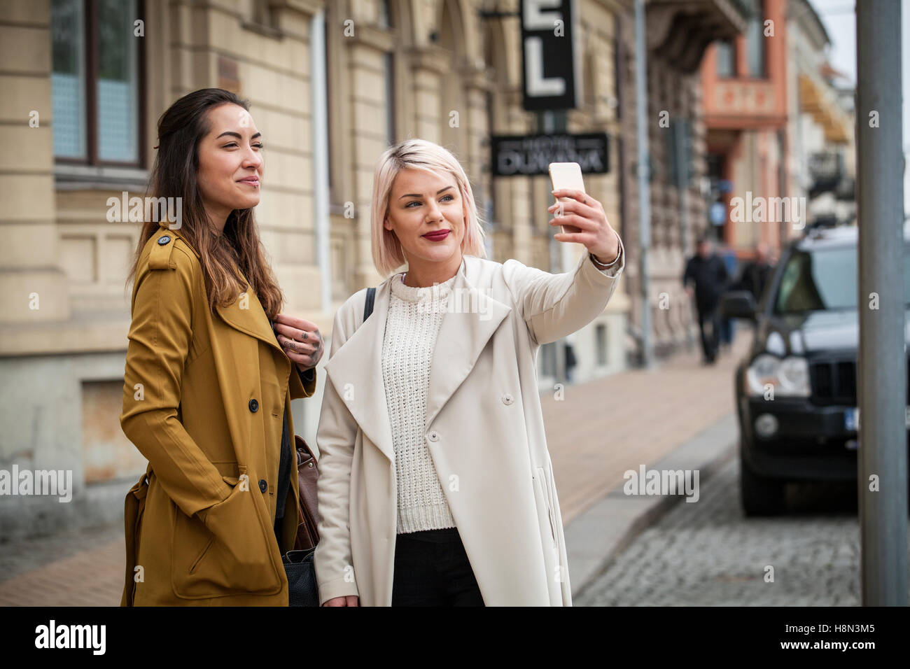 Deux jeunes femmes prenant des photos sur street selfies Banque D'Images