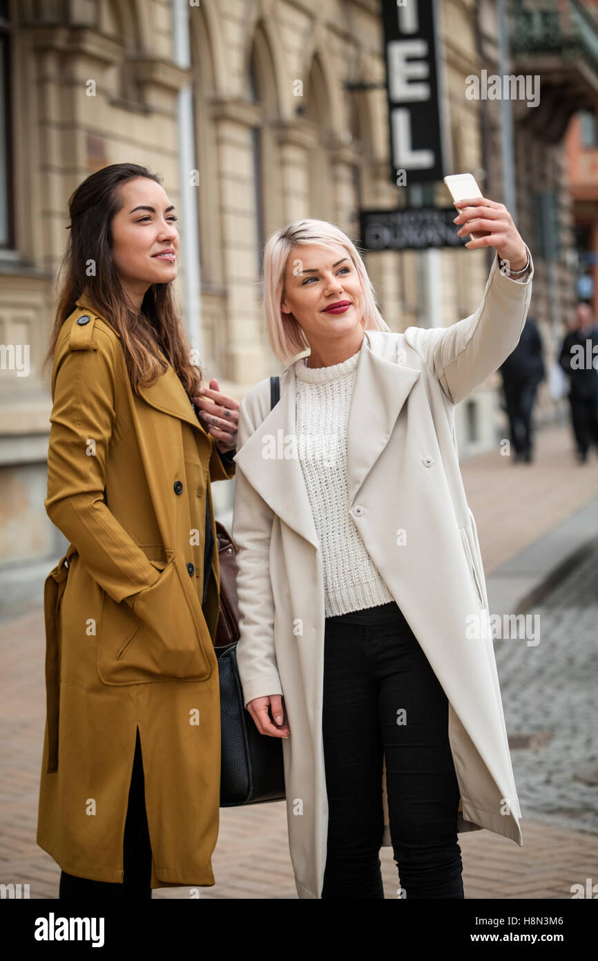 Deux jeunes femmes prenant des photos sur street selfies Banque D'Images