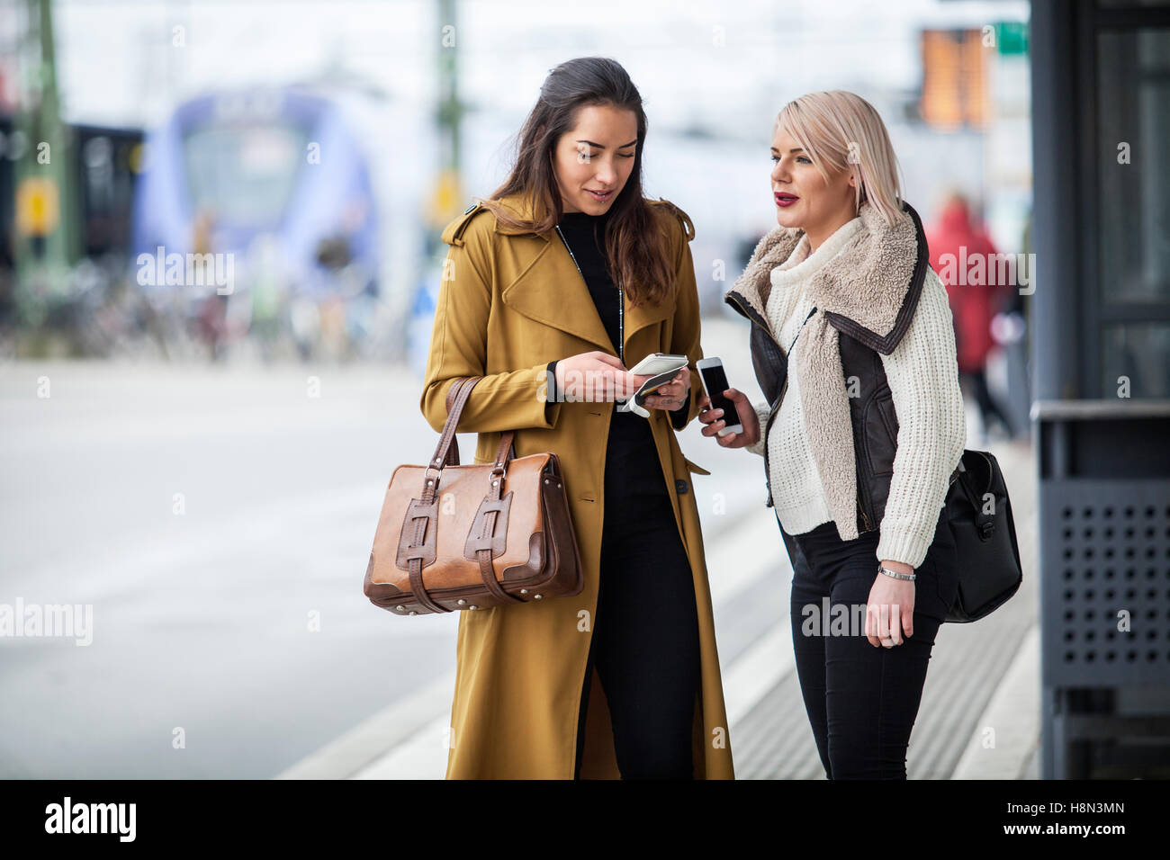 Deux jeunes femmes se tenant debout avec les smartphones Banque D'Images