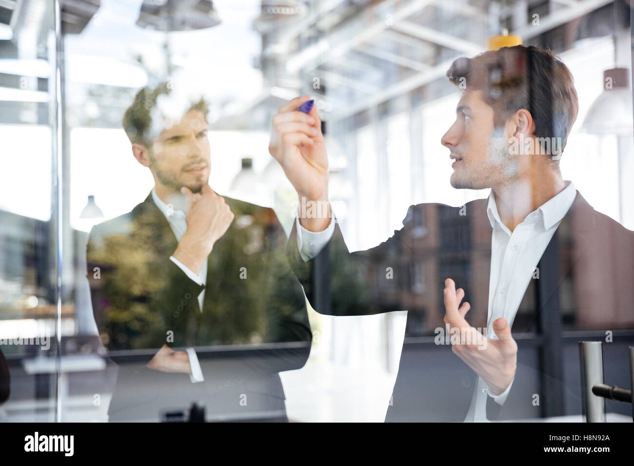 Deux jeunes hommes d'concetrated parle et écrit sur la vitre d'administration en exercice Banque D'Images