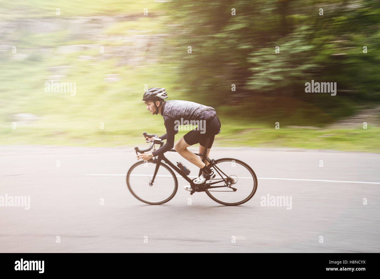 Panoramique d'un jeune cycliste tour un coin à Cheddar George Banque D'Images