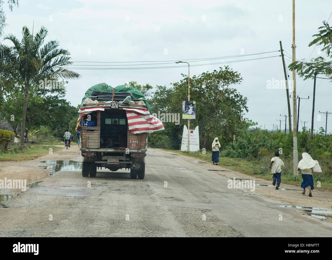 Un dala dala sur une route de Zanzibar avec les élèves dans la marche à côté de la route Banque D'Images