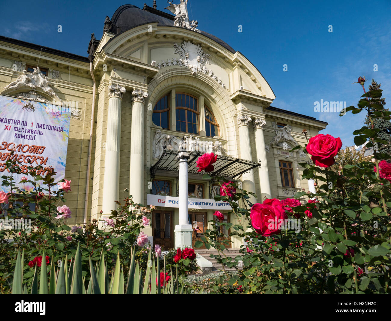 Roses rouges avec du Théâtre Dramatique de Chernivtsi Ukraine avant de Chernivtsi Drama Theatre dans l'arrière-plan. Oblast de Tchernivtsi Ukraine Banque D'Images