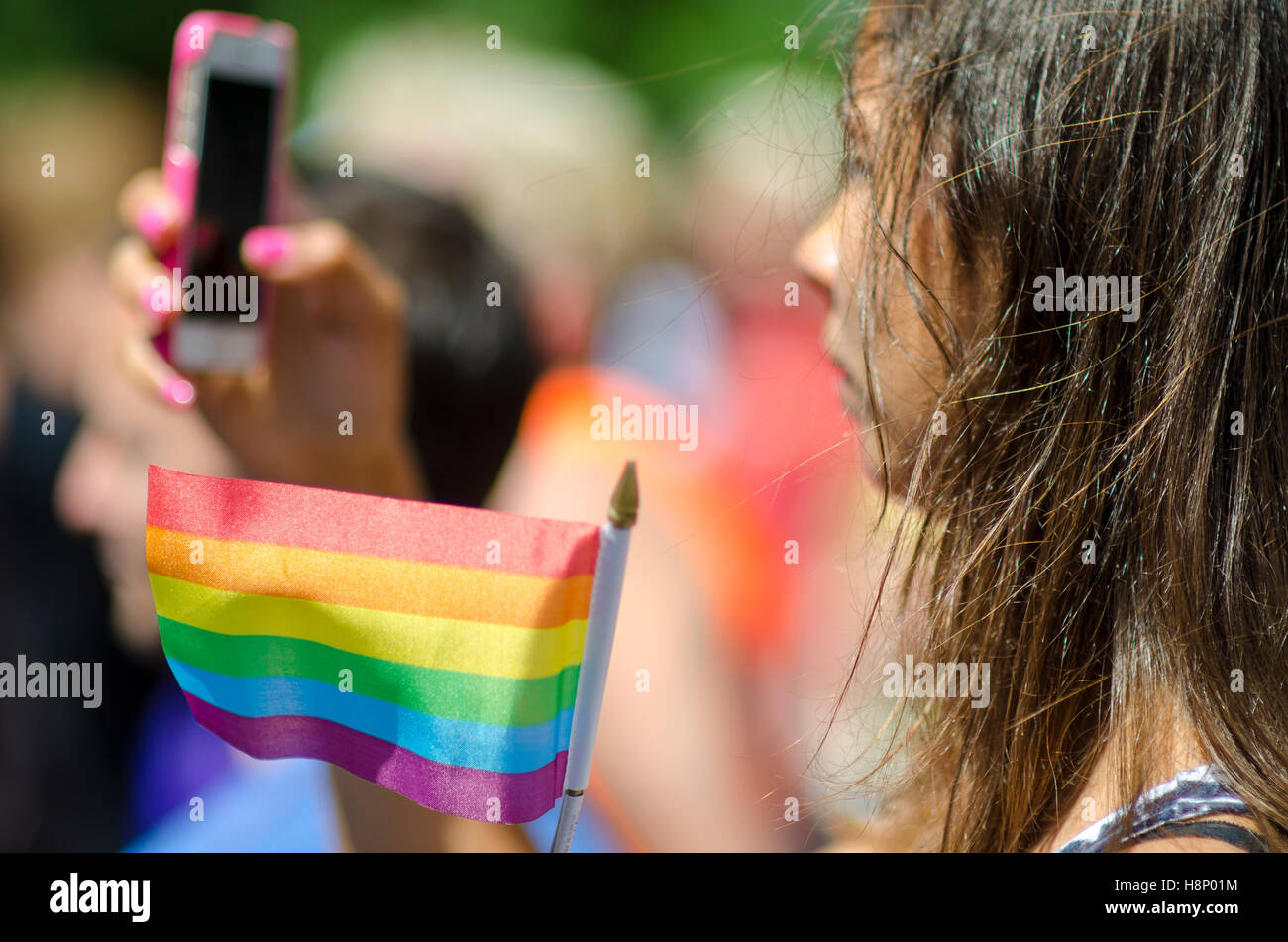 NEW YORK - 21 juin 2016 : Une jeune femme prend une photo tout en brandissant un drapeau arc-en-ciel à l'appui de la Gay Pride Parade annuelle Banque D'Images