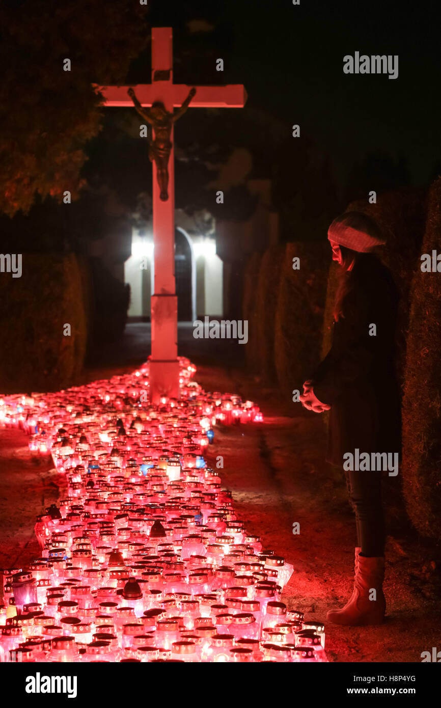 Une vue de la nuit d'une femme en prière devant la croix de cimetière à Zagreb, Croatie. Banque D'Images