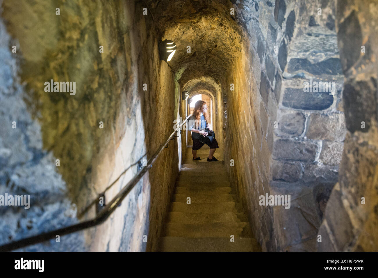 Royaume-uni, Angleterre, dans le Yorkshire, Richmond - Une jeune femme posant touristiques avec son appareil sur un escalier à l'intérieur du château de Richmond, l'un Banque D'Images