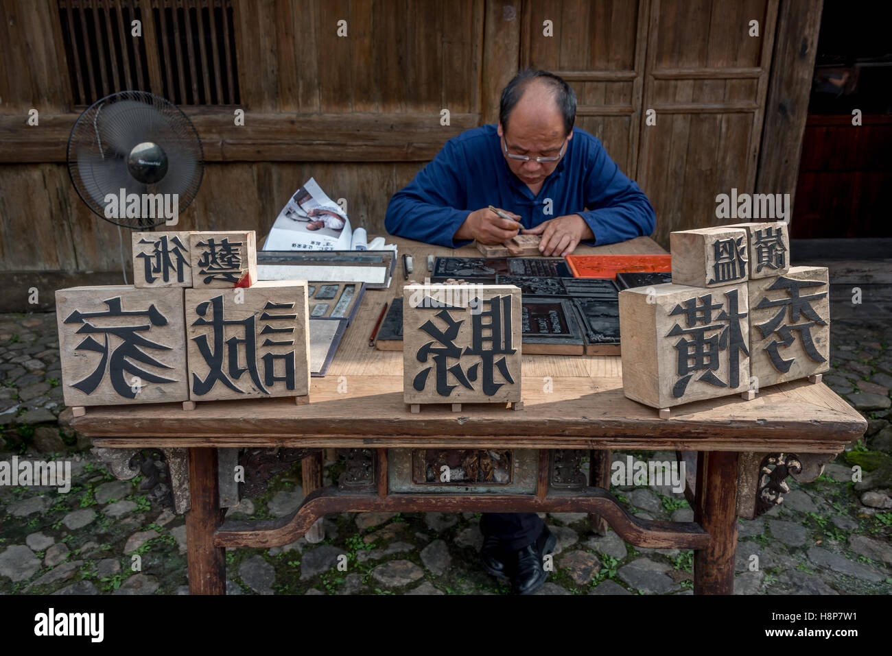 Un maître formé dans l'art chinois de l'impression à caractères mobiles en bois sculpte personnages au village Dongyuan, Huzhou, Chine. Banque D'Images