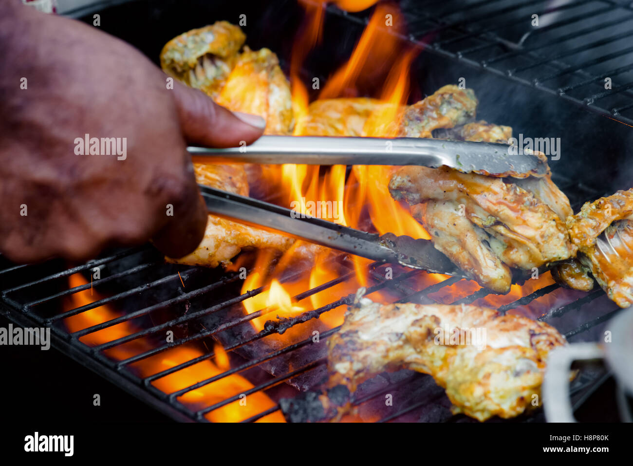 Chef cooking barbecue jerk poulet sur le grill côté transformer les aliments Banque D'Images